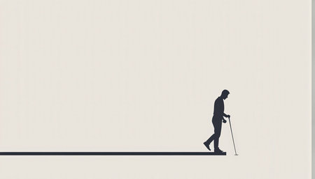 Silhouette of a man with a cane walking alone against a plain backgroundの素材