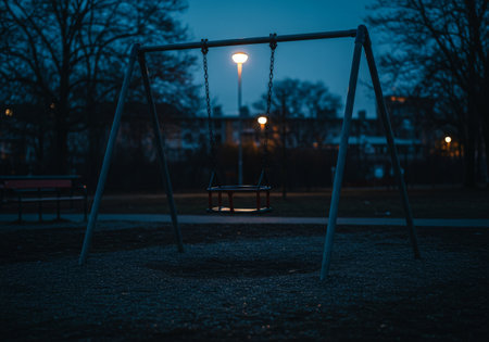 Dusks soft glow casts shadows across a colorful playground, where children swing joyfully under twinkling street lightsの素材