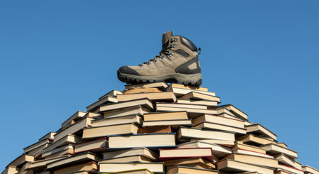 A curious student diligently studying while balancing their laptop atop a stack of booksの素材