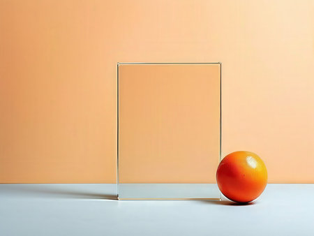 A solitary orange on a reflective surface against an abstract backdropの素材