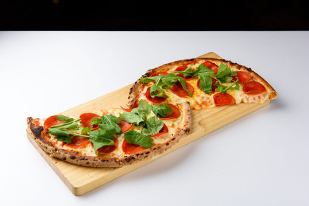 Pizza with salami and arugula on a wooden boardの写真素材