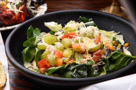 Fresh salad with spinach, olives and parmesan on wooden table