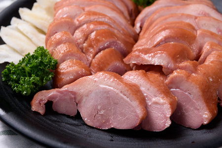 Slices of boiled pork on a black plate with parsleyの写真素材