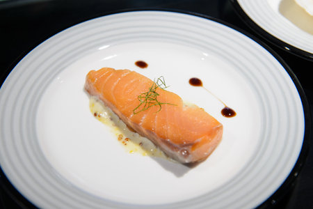 Salmon sashimi with sauce in white plate on black backgroundの写真素材