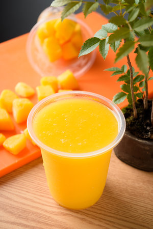 Mango smoothie in plastic cup on wooden table, stock photoの写真素材