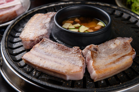 Grilled pork belly with soy sauce and pickled cucumber on black grillの写真素材
