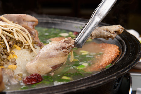 A picture of a boiled duck leg being lifted with tongsの写真素材