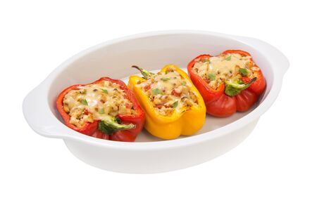 colorful baked with cheese stuffed peppers with minced turkey and vegetables in a white casserole baking isolated on a white backgroundの写真素材