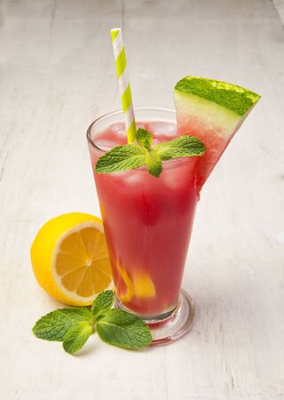 Refreshing watermelon lemonade with lemon and mint in a glass on a white wooden tableの写真素材