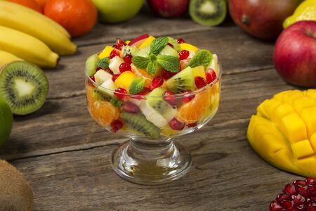 Winter fruit salad in glass salad bowls with fresh ingredients on an old rustic wooden table. Selected focus.の写真素材