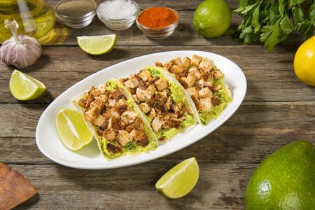 Chicken tacos with avocado cream sauce traditional Mexican dish on a wooden rustic table with ingredients. Selected focusの写真素材