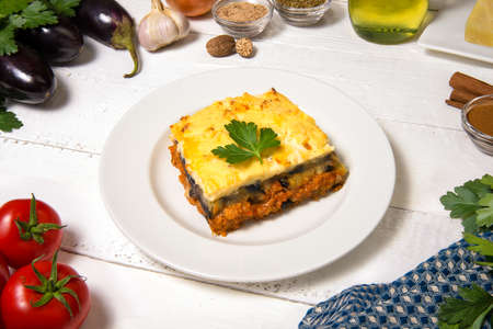 Greek Moussaka close up in dish with the ingredients on the white rustic table.の写真素材