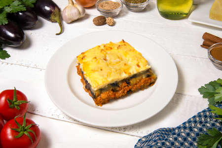 Greek Moussaka close up in dish with the ingredients on the white rustic table.の写真素材