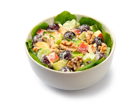 Waldorf salad of apples, celery stalks, walnuts, grapes, lettuce in a white salad bowl isolated on white background.の写真素材