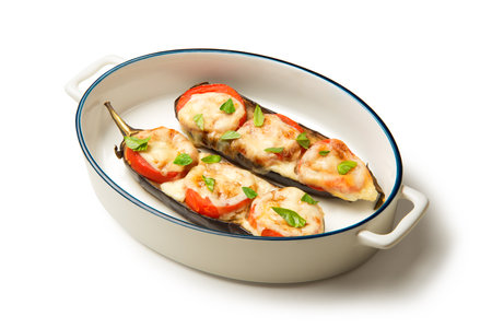 Caprese of baked eggplant tomatoes and mozzarella in an oval baking dish isolated on a white background.の写真素材