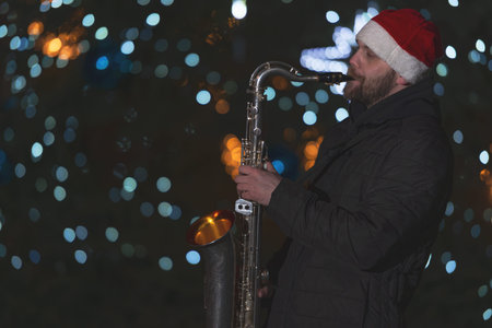 man playing the saxophone in front of a Christmas tree in the square. The man is wearing a Christmas...
