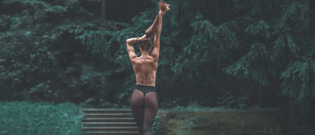 the girl stands facing the lens and looks into the forest. the girl has long hair that already covers her entire back. She has polka dot stockings on her feet. Behind the woman areの写真素材