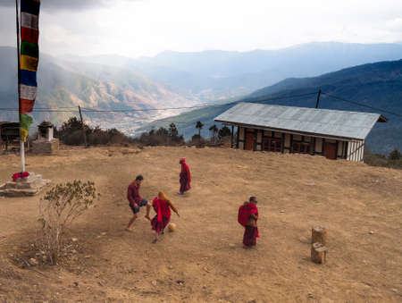 Thimphu/ Bhutan - February 28, 2016:  young boys  Buddhist monks in their traditional red clothes play football before a snowstorm in the monastery Hadjoding high in the Himalayan mountains.のeditorial素材