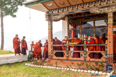Punakha/Bhutan - March 1, 2016: young women monks of the Buddhist monastery in their traditional red robes before classes against the background of the Himalayan mountainsのeditorial素材