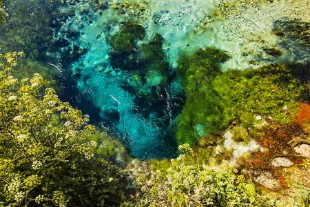 Beautiful bright turquoise spring Blue Eye (Syri i Kalter) Saranda, Albania, river Bistrice. Top view with pebbles, stones and plants around. Can be used as abstract nature water background.の写真素材