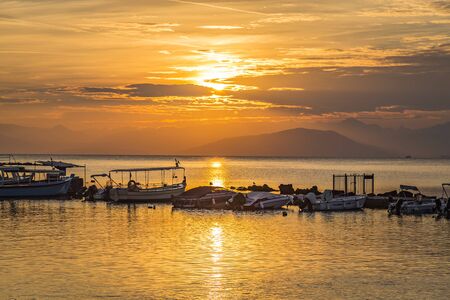 Early morning sunrise view of fisherman boats in Halikiopoulou lagoon. Kanoni, Corfu island, Greece on background of rising sun.の写真素材
