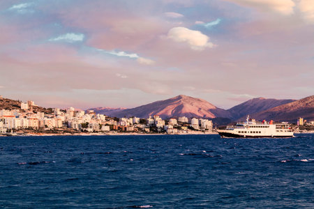 Small Ferry boat in gulf of Saranda, Albania on background of Albanian mountains. Sunset, cloudy...