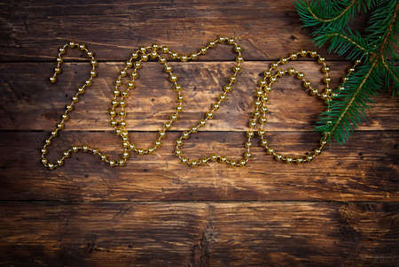 Decorative design Christmas with New year 2020, on a vintage wooden brown table. Top view, flat lay. Christmas tree branch and 2020 written by bead christmas garland. Copy spaceの写真素材