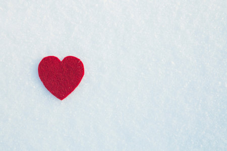 Red felt heart on the snow white background. Text space. Empty template.