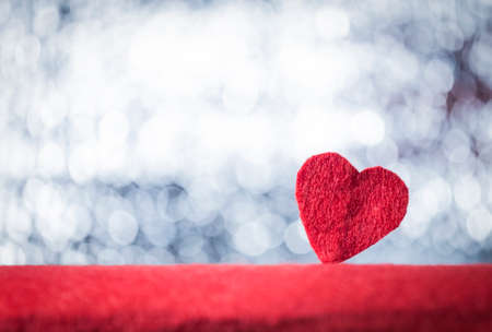 Red handmade felt heart standing on beautiful bokeh background. Vintage style. Valentine's Day concept. Text space. Empty template.の写真素材