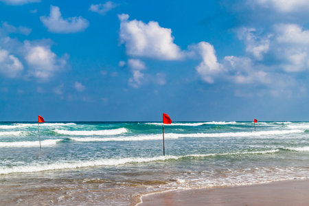 Swimming is dangerous in sea waves. Red warning flag flapping in the wind at stormy weather on the...