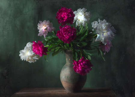 Classic still life with beautiful white and purple peony flowers bouquet in ancient jug. Art photography.の写真素材