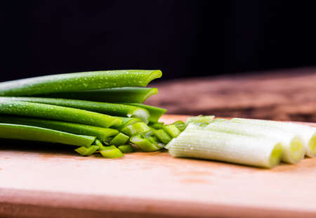Chopped scallion or shallot or spring onion greens close up on wooden board. Green salad side dish preparation. Vegan raw food.の写真素材