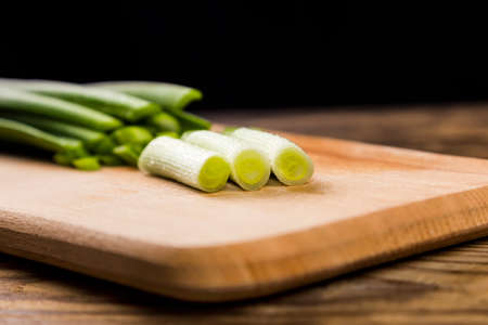 Chopped scallion or shallot or spring onion greens close up on wooden board. Green salad side dish preparation. Vegan raw food.の写真素材