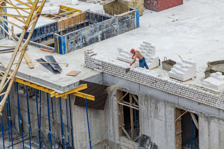 Bricklayer worker makes a wall of white silicate bricks on a construction site of a big residential house.の写真素材
