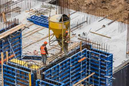 Concreting work at the construction site. ? onstruction workers pour liquid concrete from cement...