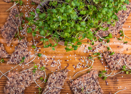 Crunchy crispy seed homemade bread decorated with microgreen sprouts and growing microgreens on a wooden table. Close up flat lay view. Copy space for text.の写真素材
