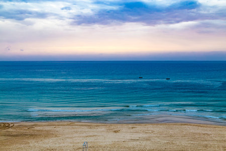 Twilight time and sunset at the beach in Netanya, Israel, Mediterranean sea. Overcast sky, foam and...