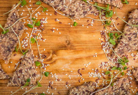 Crunchy crispy seed homemade bread decorated with microgreen sprouts on a wooden table. Healthy snack. multigrain cereal flax, sesame and sunflower seeds. Close up flat lay view. Text space.の写真素材