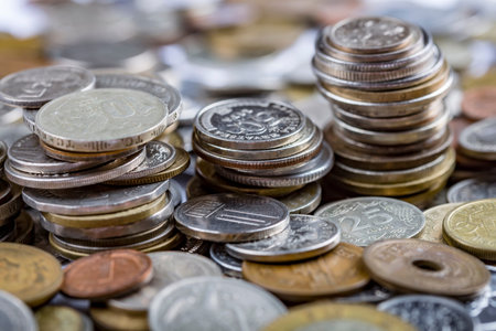 Various multi-colored coins of the currency of the whole world stacked on top of each other. The...
