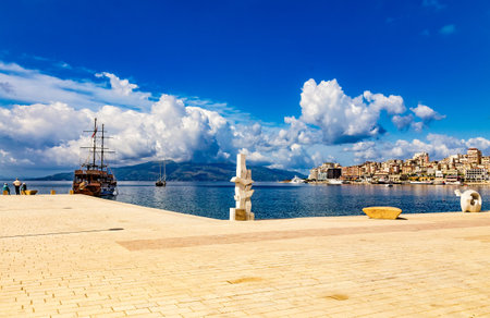 Saranda, Albania - 14 May 2021: Panoramic view of city port and town from the new modern city embankment. Modern sculptures adorn the embankment. Sunny summer day. Corfu island visible on the horizon.のeditorial素材
