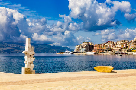 Saranda, Albania - 14 May 2021: View of city port and town from the new modern city embankment. Modern sculptures adorn the embankment. Sunny summer day. Corfu island visible on the horizon.のeditorial素材