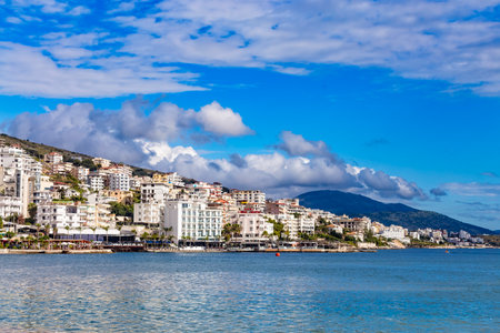 Panoramic view of Saranda bay and town and hotels along the coast, Albania. Sunny summer day. Beautiful clouds in the sky. Albanian mountains visible on the horizon. Calm blue sea.のeditorial素材