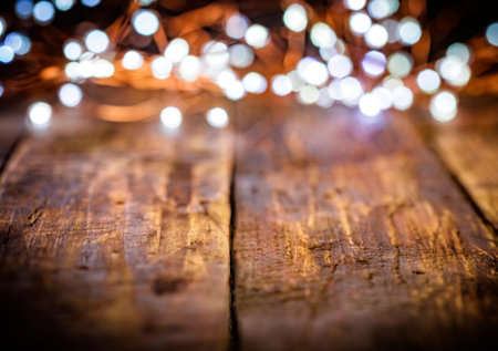 christmas garland of white and golden defocused lights on dark old weathered vintage table or wooden...