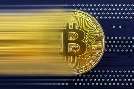 Close up of golden bitcoin crypto currency token in movement on blue circuit boardの写真素材