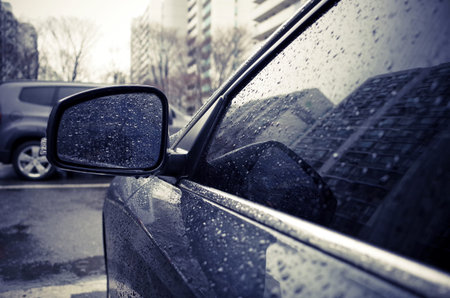 Raindrops on side rearview mirror in rainy day.