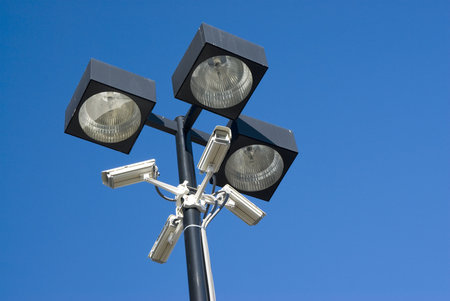 security cameras mounted on floodlights in a parking lot