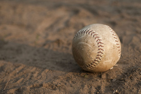 Softball laying in dirt.