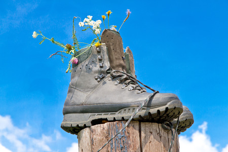 Hiking boots with flowers on a wooden stakeの写真素材