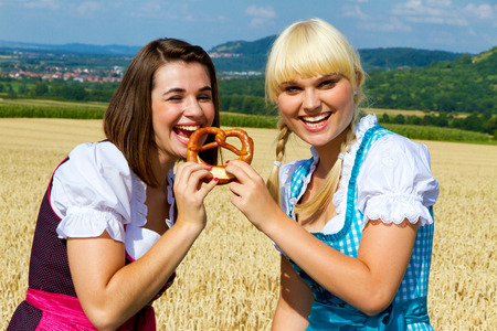 Two girls in dirndls with pretzelの写真素材