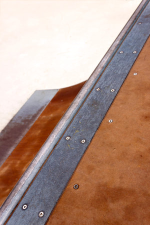 Detail of a wooden and metal quarter pipe ramp with rail in a skate park. Copy-space for placing...